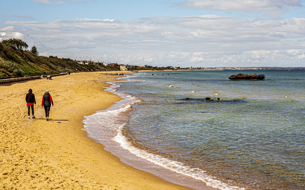 Two people walking away down the beach