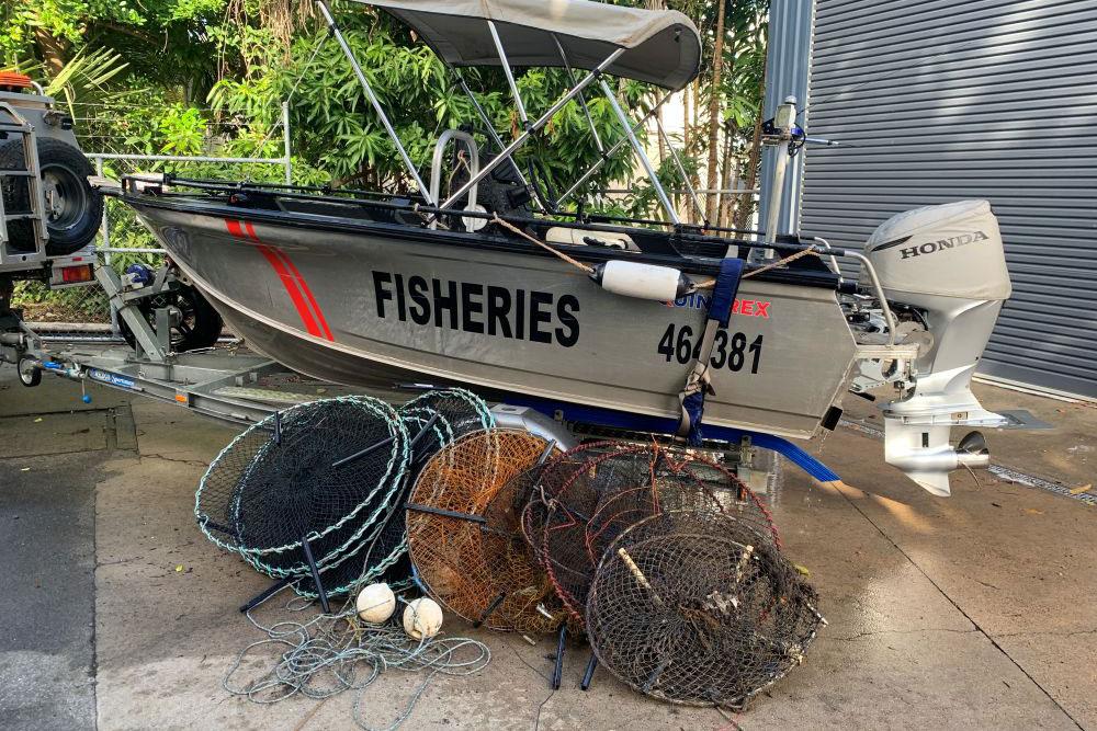 Fisheries boat on a trailer with crab pots in front on the ground.